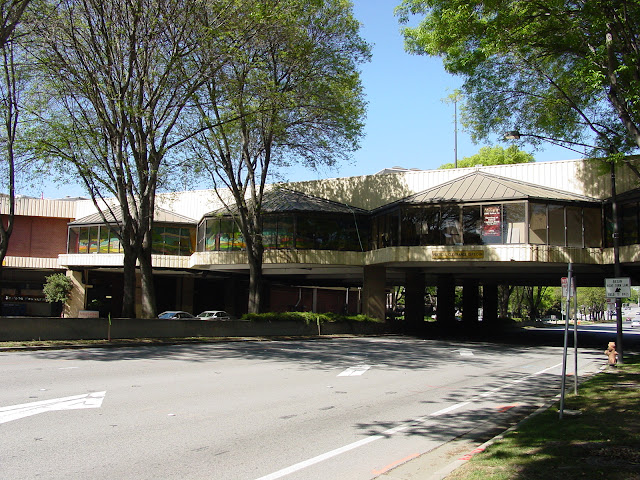 Exterior view of the Vallco Mall skybridge crossing Wolfe Road in Cupertino with trees and mall buildings in the background